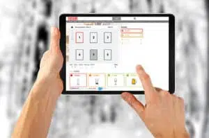 Hand holding a computer and a tablet, symbol of technology and communication, with writing and finger gesture.